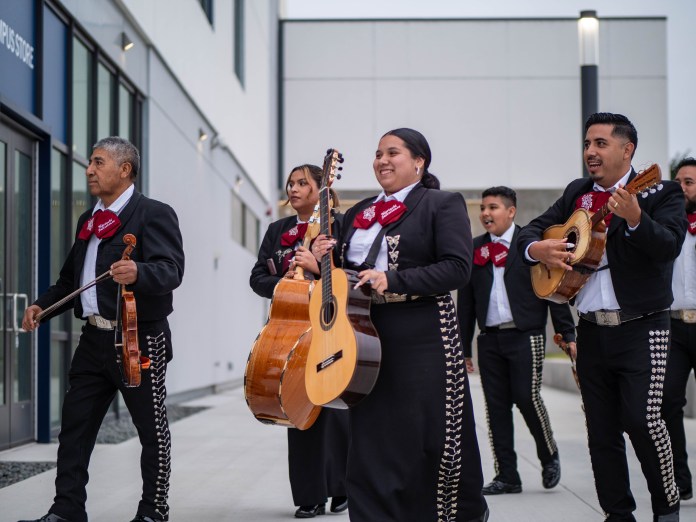 Mariachi band arriving dressed in black, white, and marron carrying their instruments.