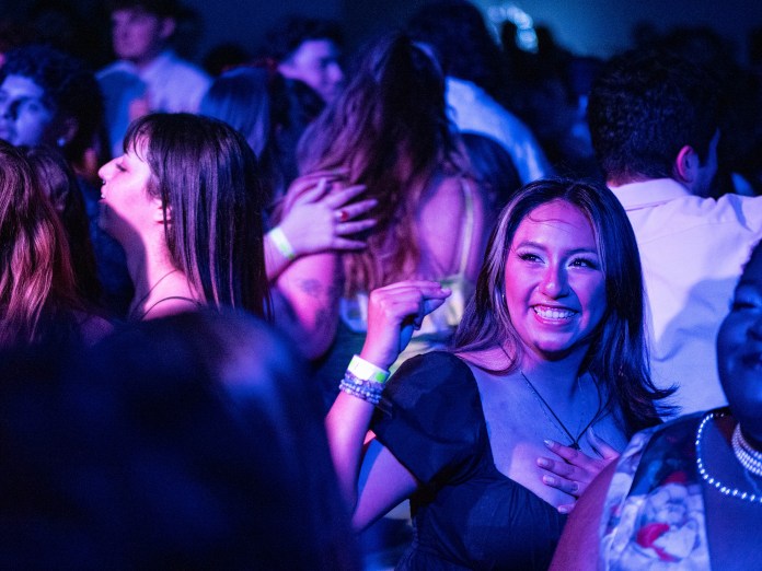 Crowd of people on the dance floor with blue and purple lighting.