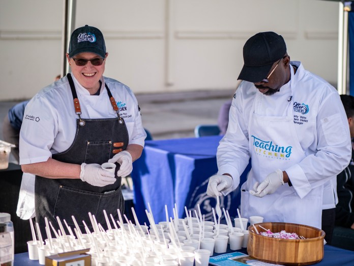 Two chefs prepping small cups for taste tests.
