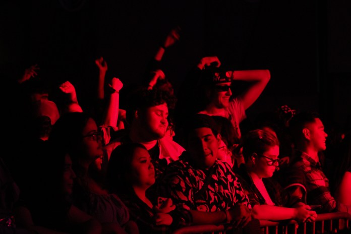 Crowd of people at a concert with red lighting.