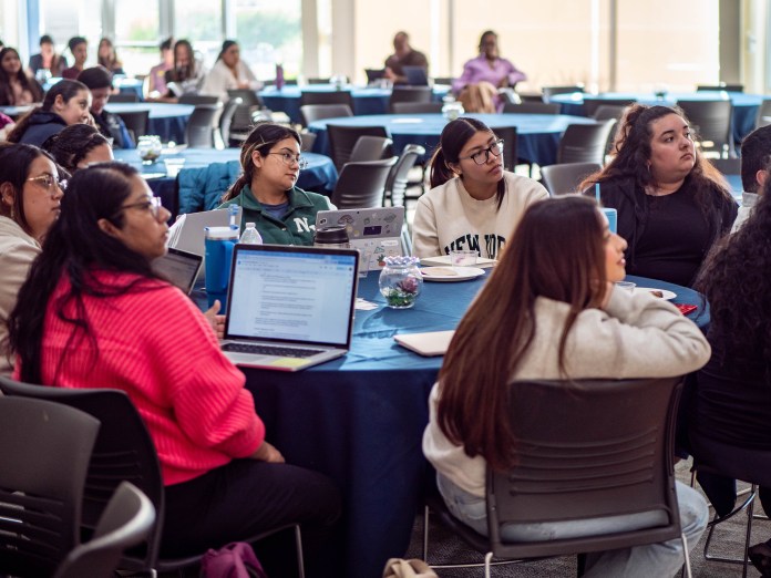 Group of students sitting at a round table with their laptops.