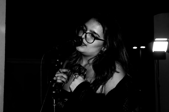 Black and white photo of singer Roxy O singing at a microphone.
