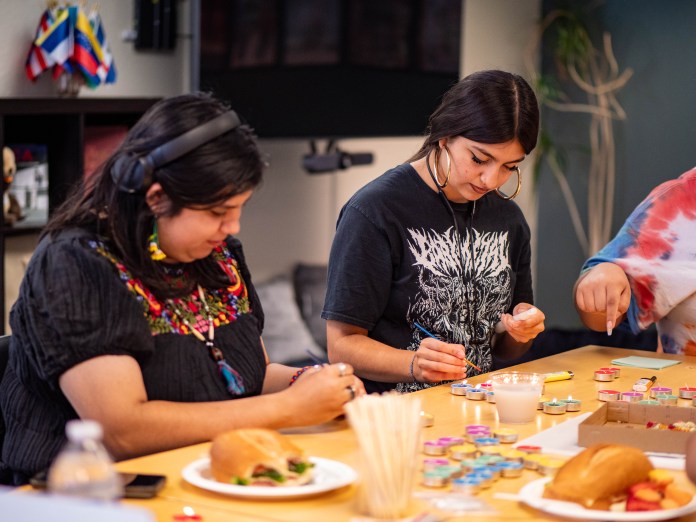 Two event attendees participating in a craft with candles and food on the table.