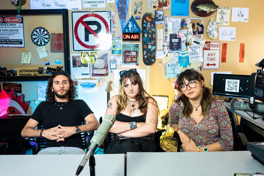 Image of the three otter media staff sitting at a table looking into the camera.