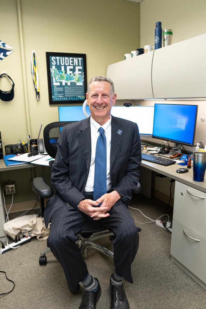 Image of Dean of Students, Dr. Reuben Rodriguez wearing a suit in his office