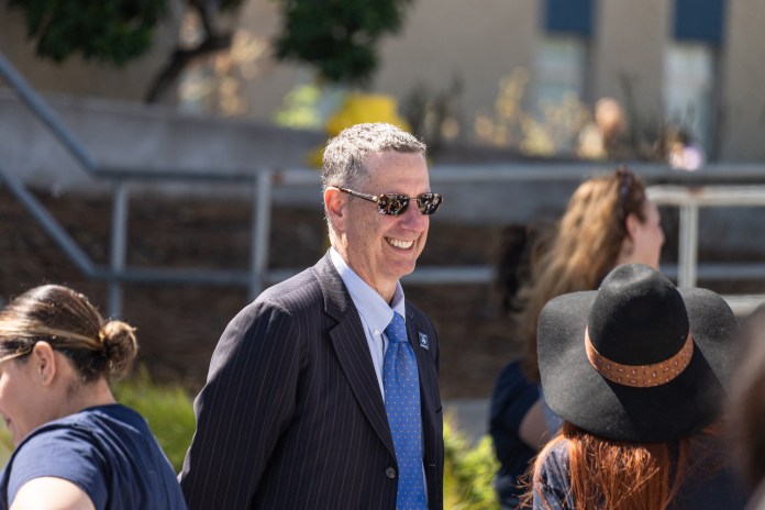 Image of Dean of Students Dr. Reuben Rodriguez smiling in front of students.