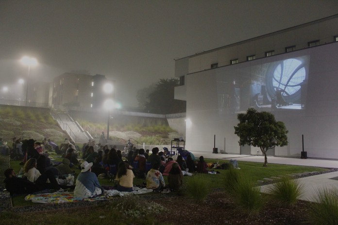 Image of students watching Doctor Strange outside the backside of the Otter Student Union Building.