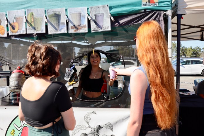 Image of boba vendor at the farmers market handing a boba tea to one of the students.