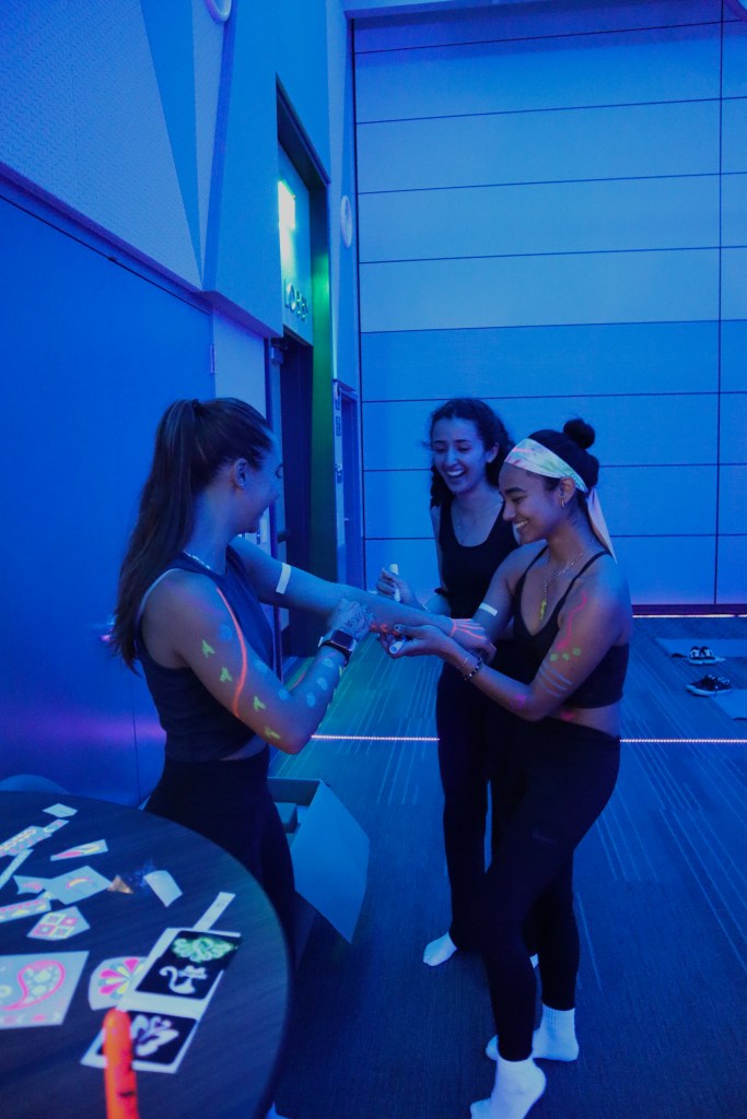 Image of 3 students putting on glow in the dark paint