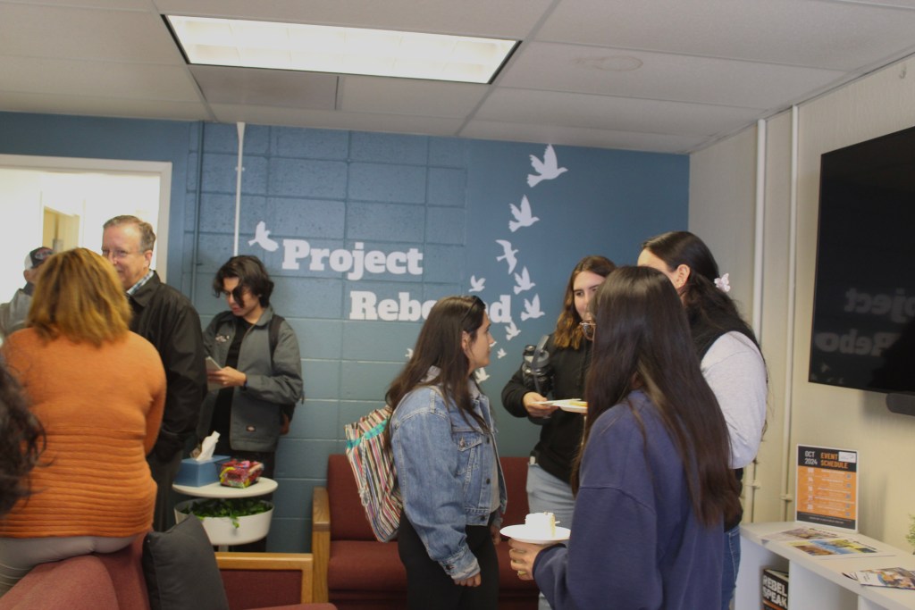 Picture of the inside of the project rebound building with many people inside mingling and socializing. Pictured in the background is project rebounds mural.