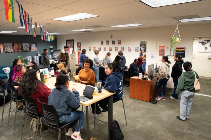 Picture of students sitting in tables eating pozole and socializing.
