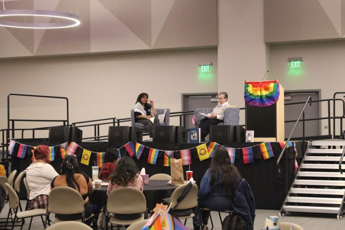 Photo of two guest speakers on a stage sitting in chairs while talking to their audience